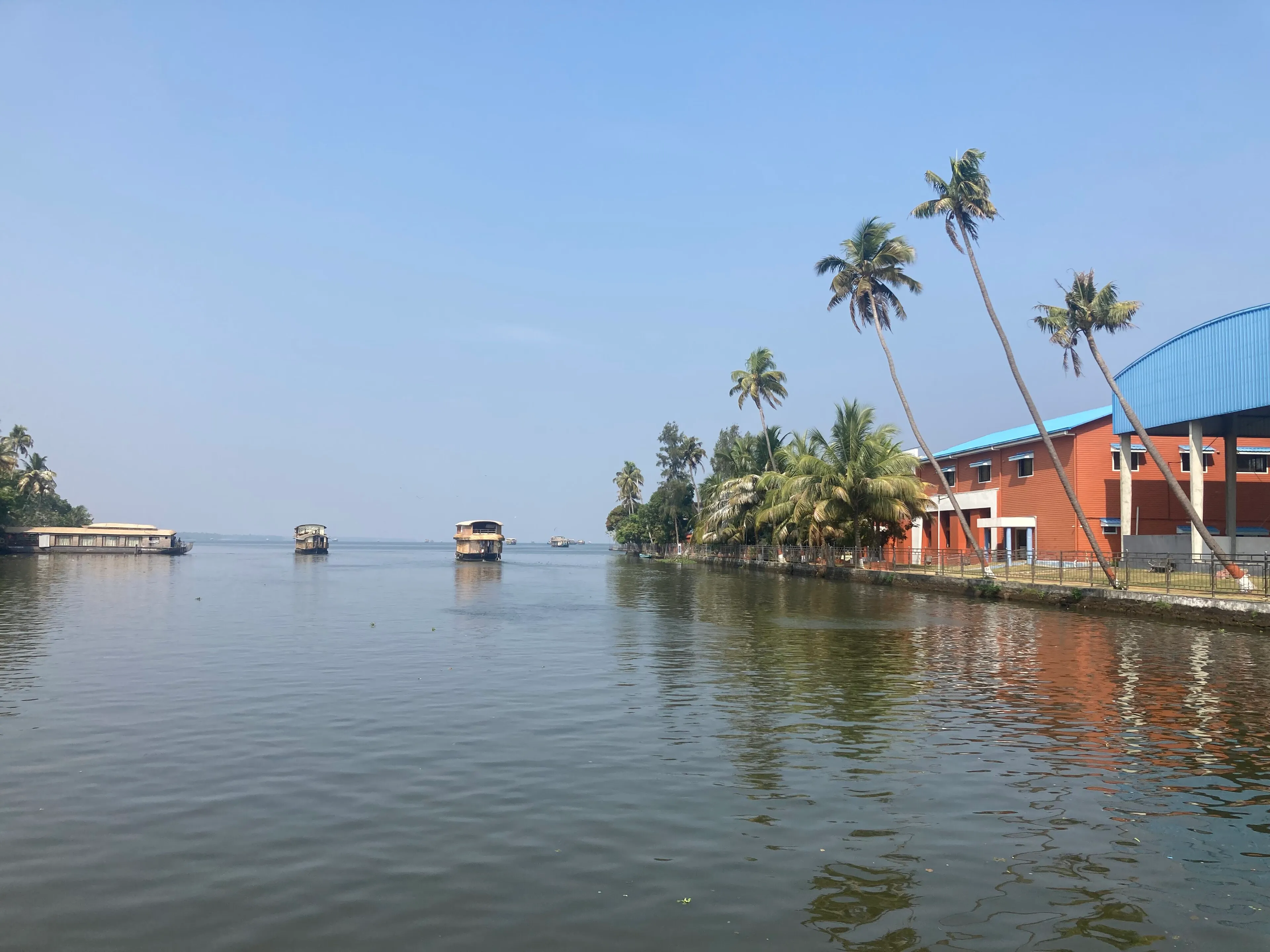 Kerala kettuvallam houseboat on the Alleppey backwaters framed by coconut palms