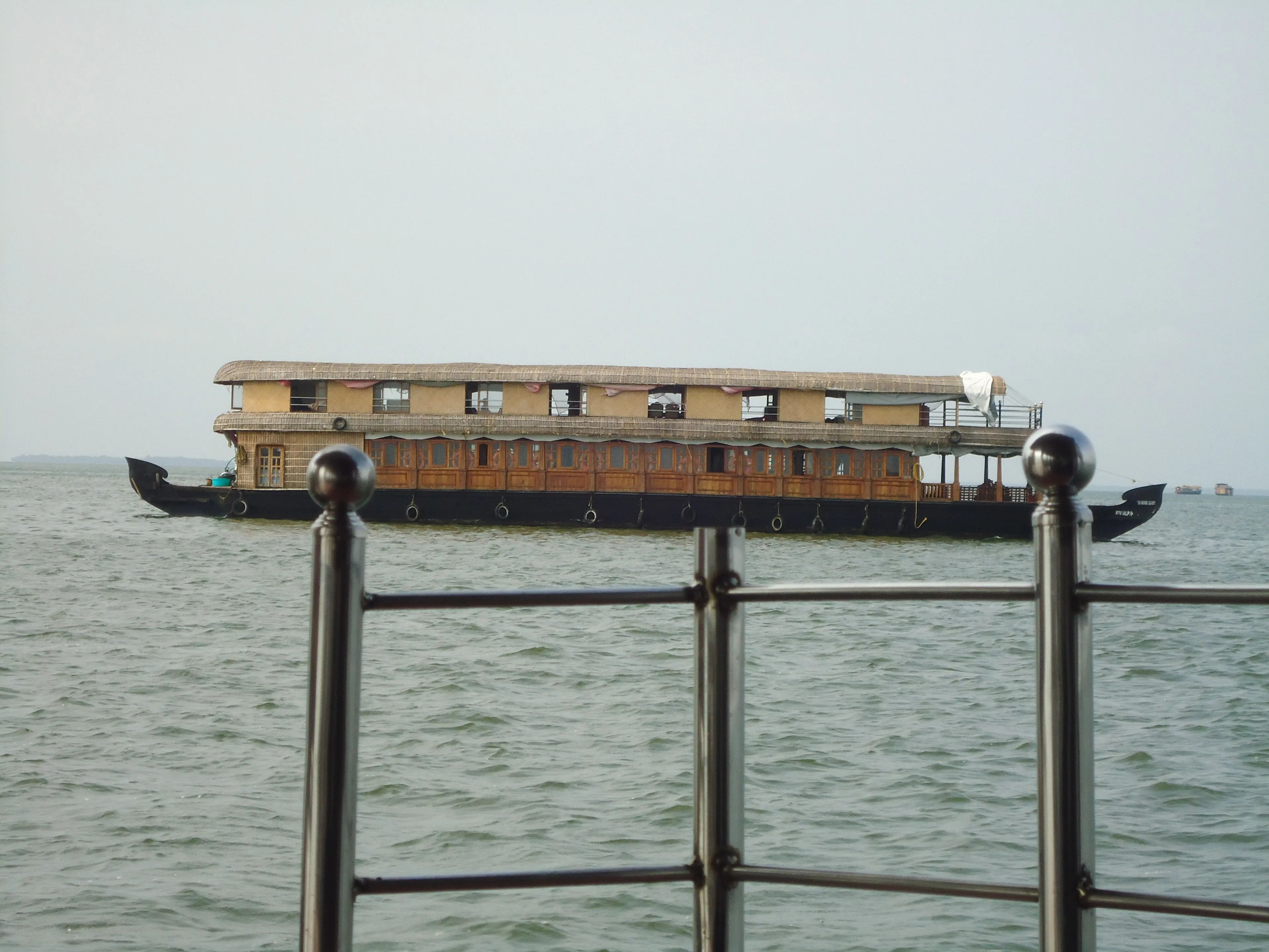 Calm Alleppey Kerala backwater canal lined with coconut palms near a moored houseboat