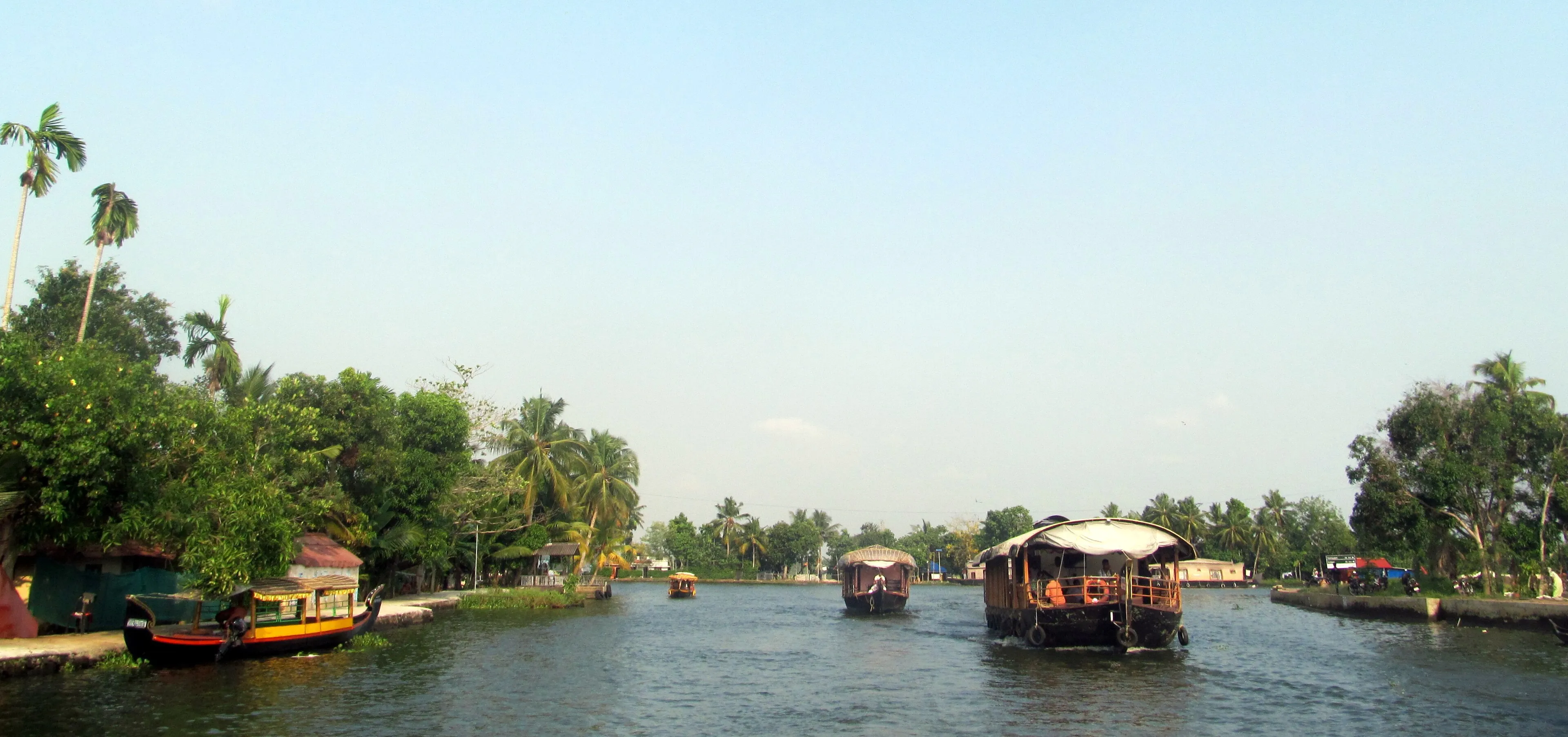 Traditional Kerala kettuvallam houseboat cruising the palm-lined Alleppey backwaters at golden hour